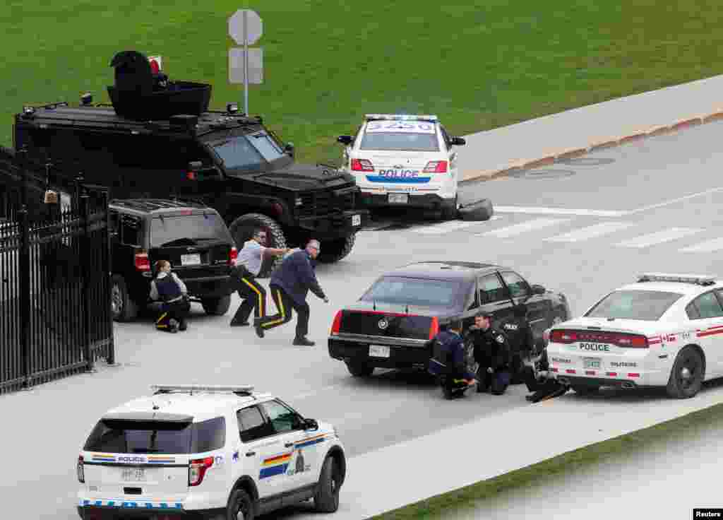 Police officers take cover near Parliament Hilll following a shooting incident in Ottawa, Canada.