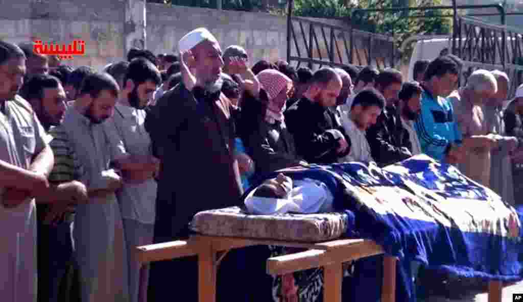 Syrians participate in the funeral prayer for Youssef Ghazi al-Sarmani, who was killed in fighting between rebel and government forces, May 27. The logo in red reads &quot;Talbiseh&quot;. 